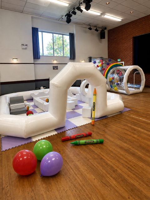 Crayon themed white soft play setup with bubble house and colourful balloons
