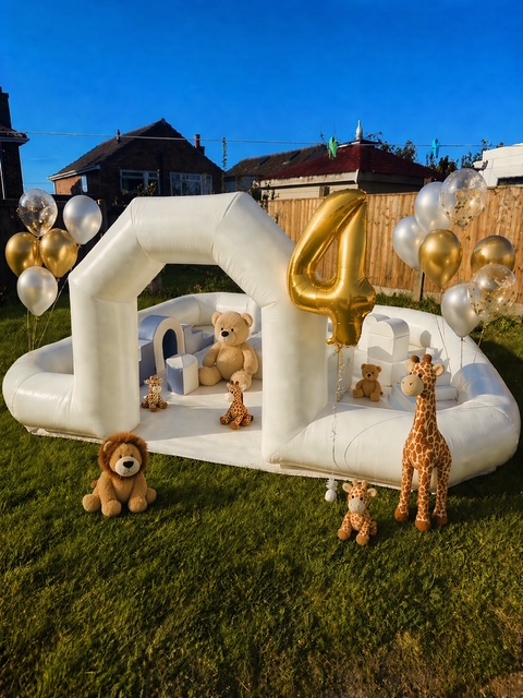 White bouncy castle setup with gold number four balloon and safari toys