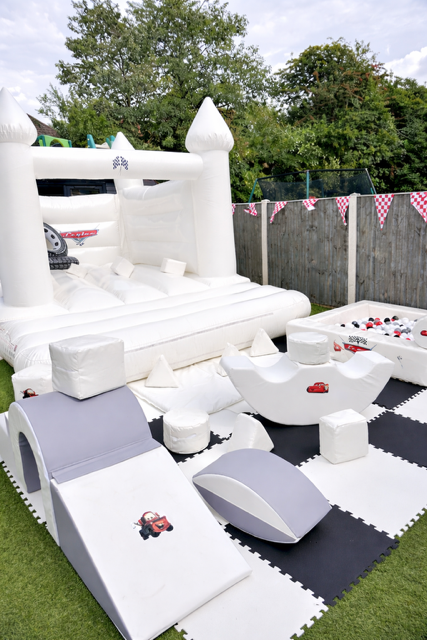 Racing themed white bouncy castle with white and blue soft play ball pit